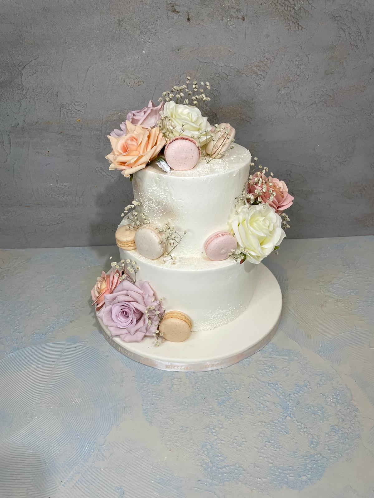 Pastel güller ve makaronlarla süslü iki katlı butik düğün pastası
